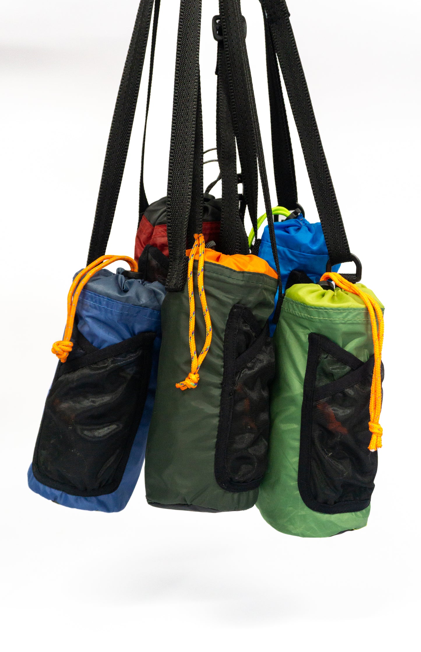 The image is of five bottle holder bags suspended from the top, they are all in different colours with black webbing straps and black mesh pockets on the front. They each have a black draw closure with an orange draw cord